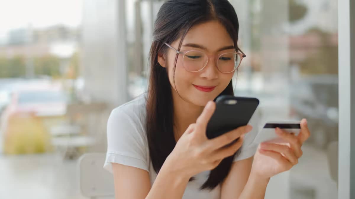 Young woman orders and pays at the restaurant directly at the table via her smartphone